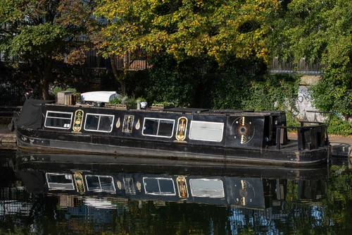 The narrowboat Xanadu moored on the canal, black hull mirrored in still water