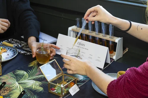 Guests pipetting elixirs from test tubes into their drinks at the table