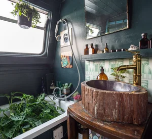 A bathroom with a carved tree-trunk basin and brass tap