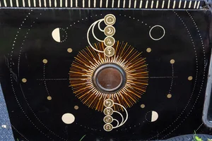 Painted panel of a golden solar orrery ringed with moon phases